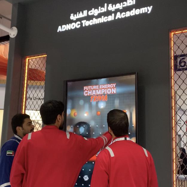 Students and guests play the Plinko Trivia Challenge at the ADNOC Technical Academy booth during a busy Dubai event